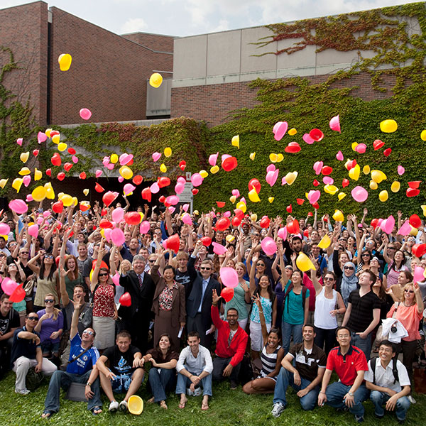 A group of Osgoode faculty throw hard hats into the air.