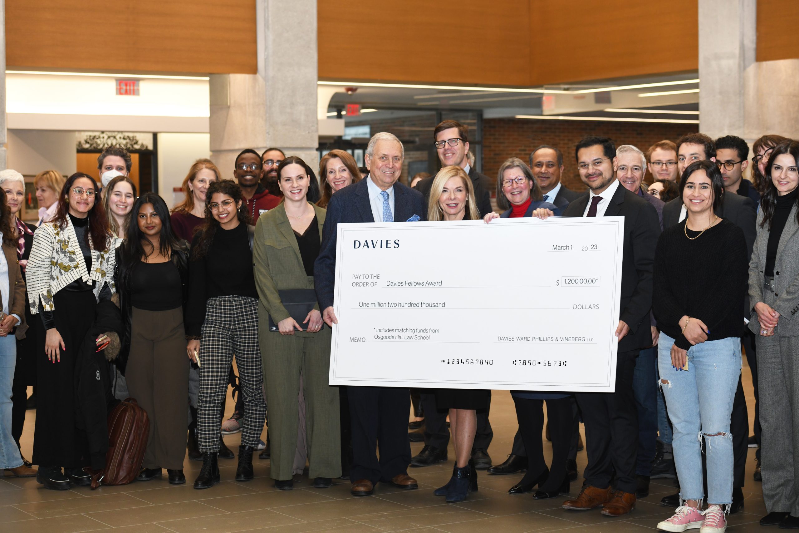 Senior Davies lawyers holding a large cheque for $1.2 million surrounded by Osgoode students.